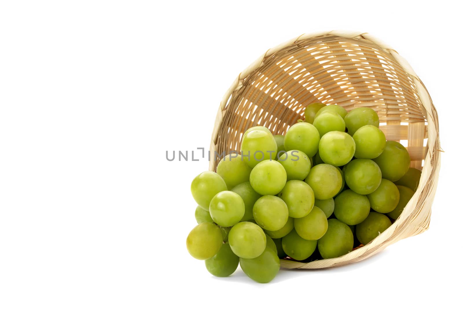 A bunch of green grapes in a weave bamboo basket. Isolated on white background.