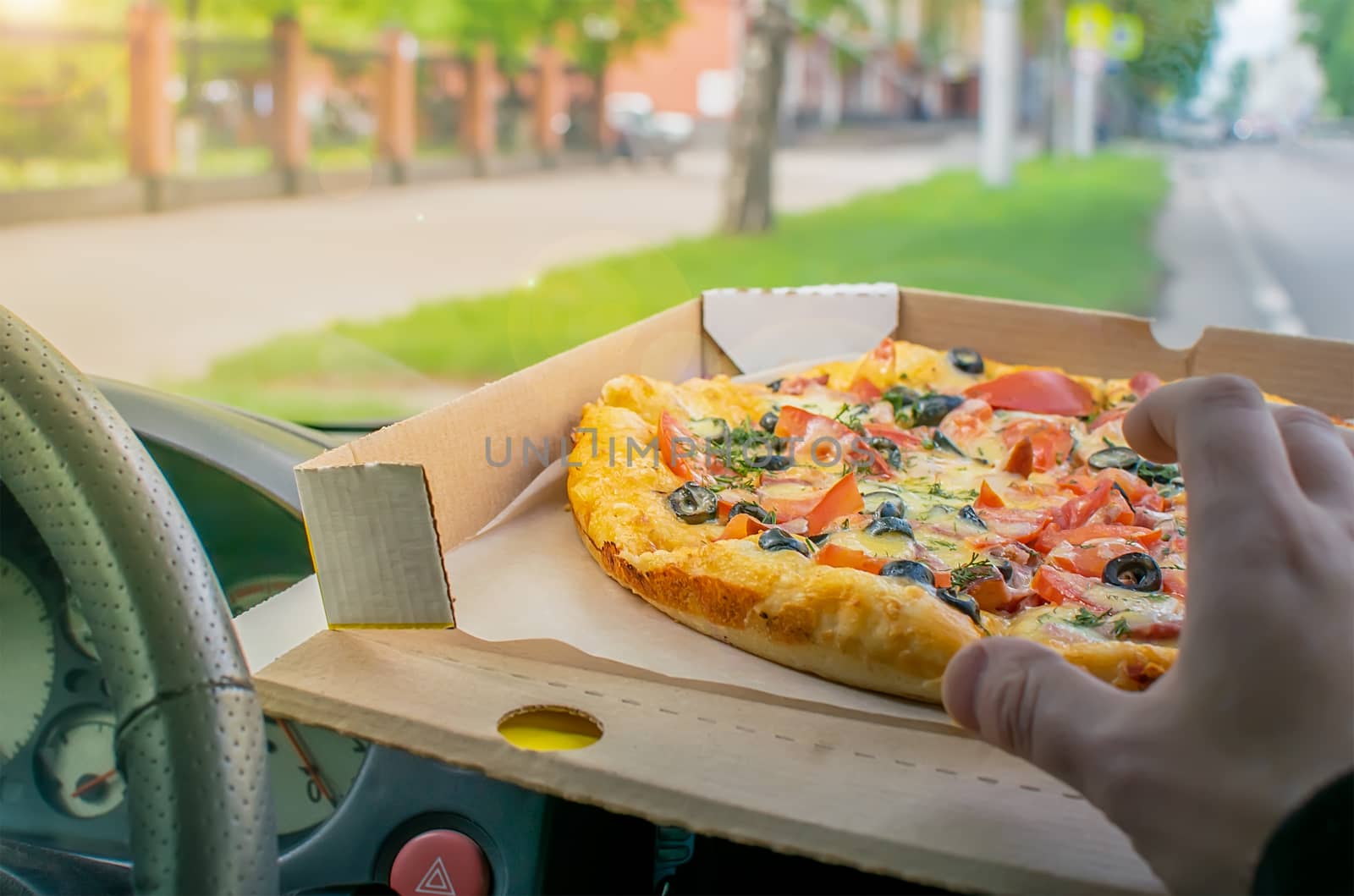 car driver hand reaches for pizza during lunch break at work