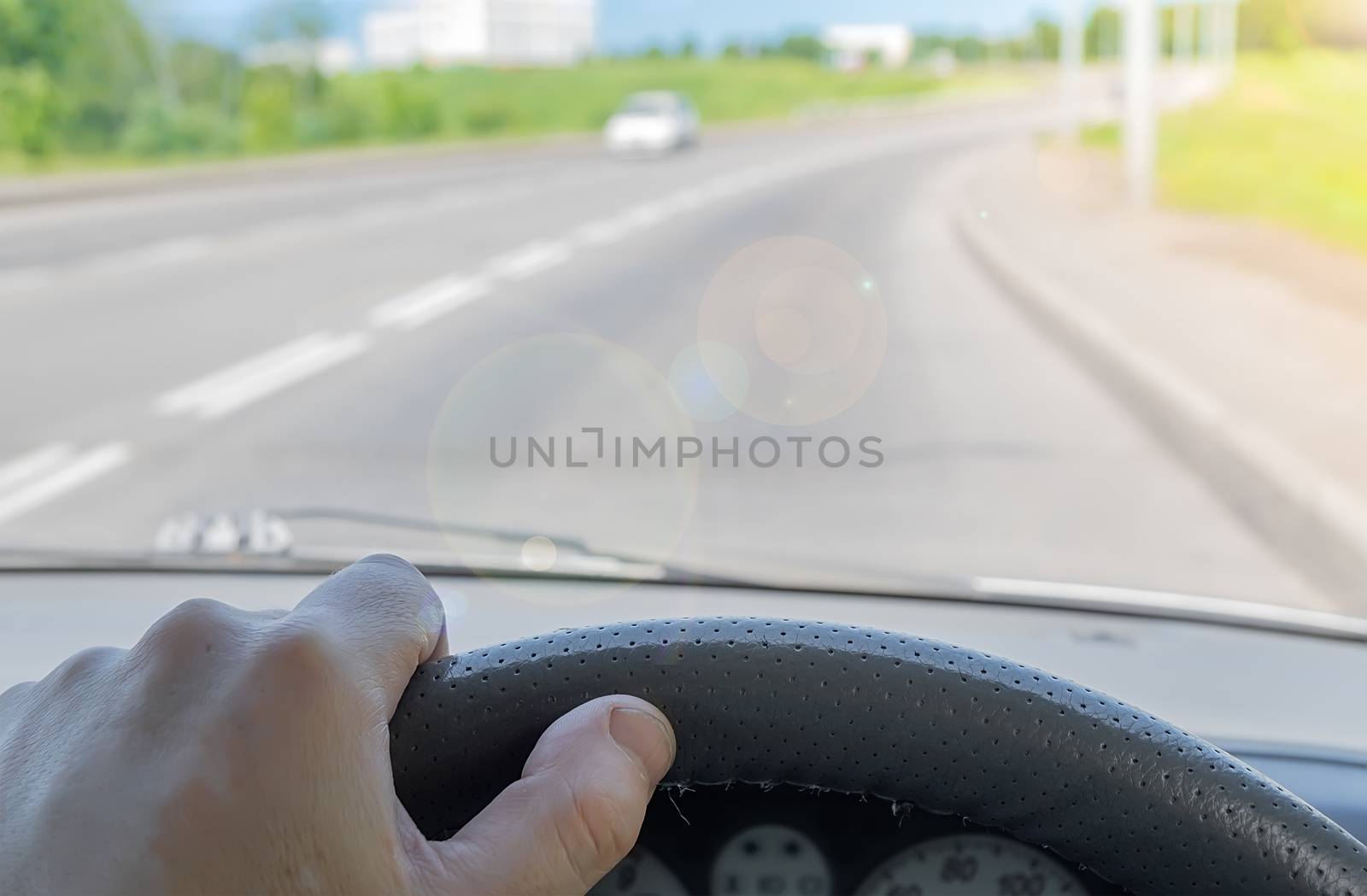 driver hand on the steering wheel of a car that is passing on a country highway by jk3030