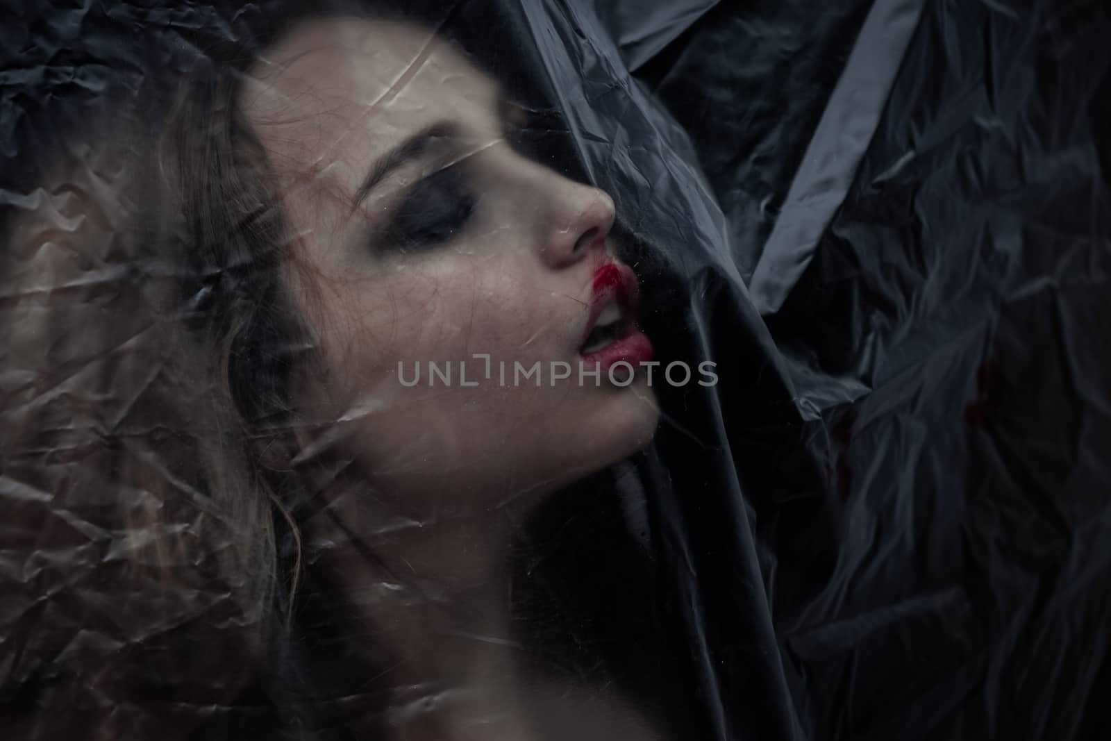 Young beauty sad woman trapped behind a plastic sheet as protection against COVID-19. Nicely fits for book cover