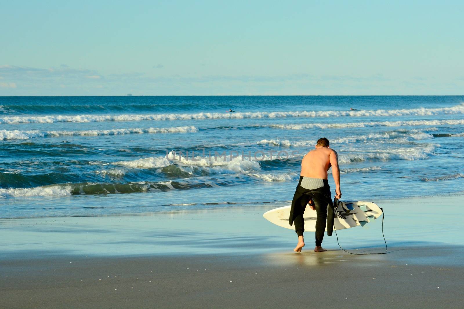Papamoa Beach, Papamoa, New Zealand – July 07, 2019: an unidentified surfer preparing to enter the sea. by Marshalkina