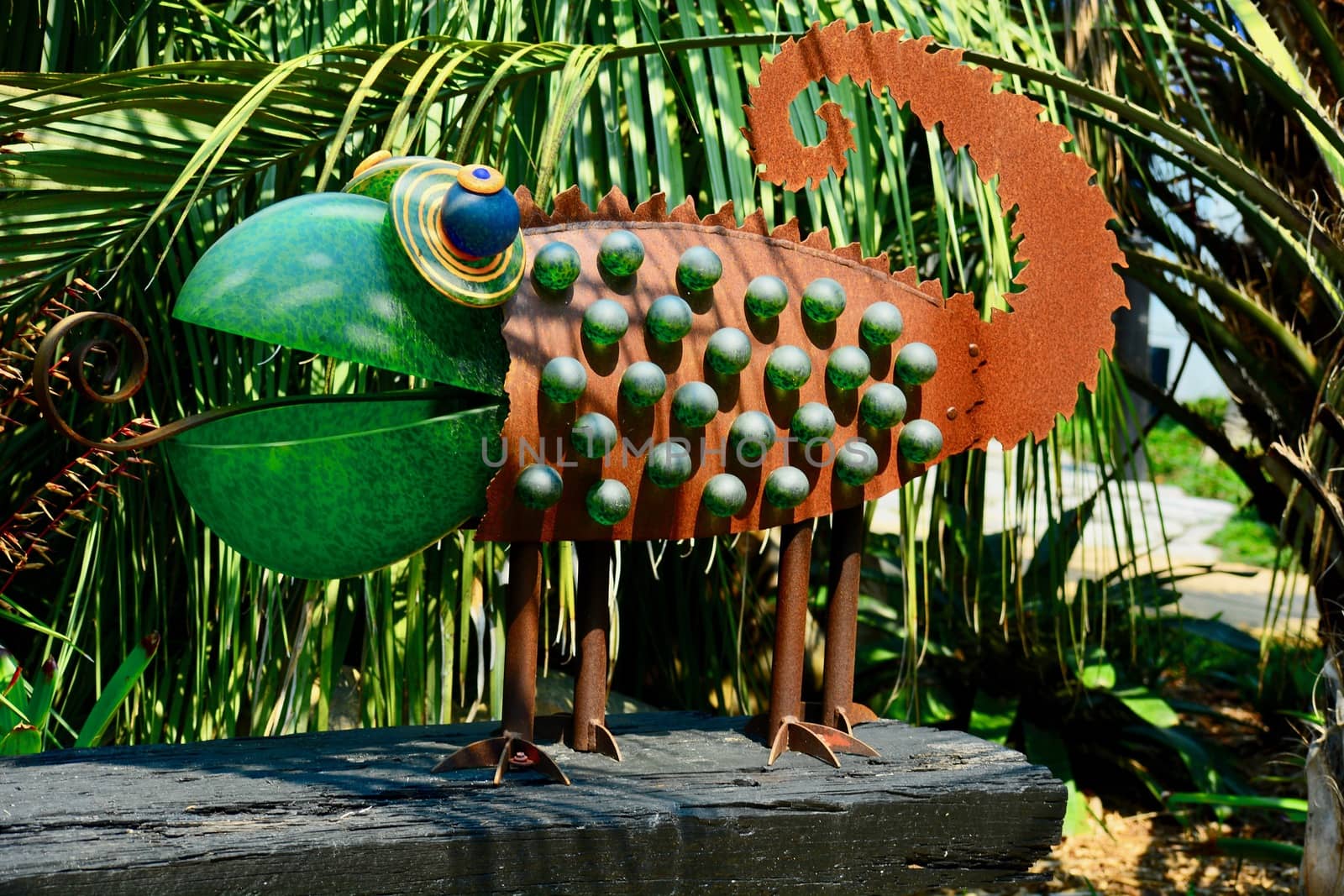 Funny garden sculpture representing a chameleon. Glass and rusty metal as its building elements.