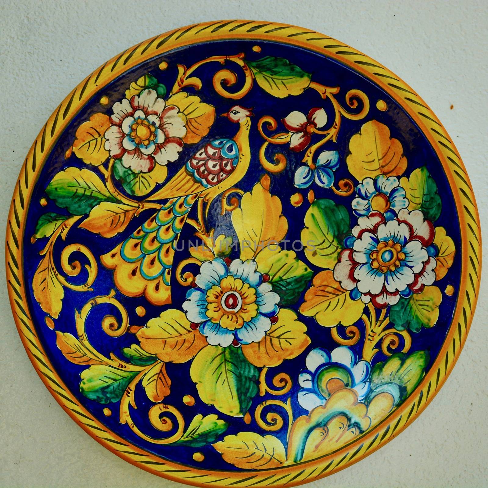 Decorative porcelain plates, cheerful and  brightly coloured, on an outside of a house wall. by Marshalkina