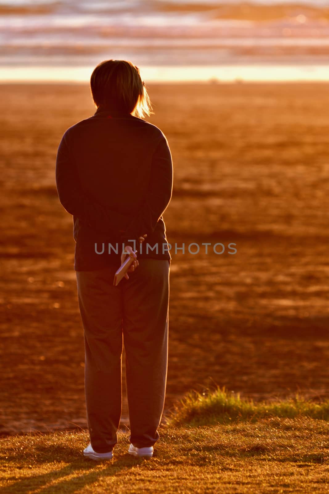 An unidentified person enjoying sunset on a beach.