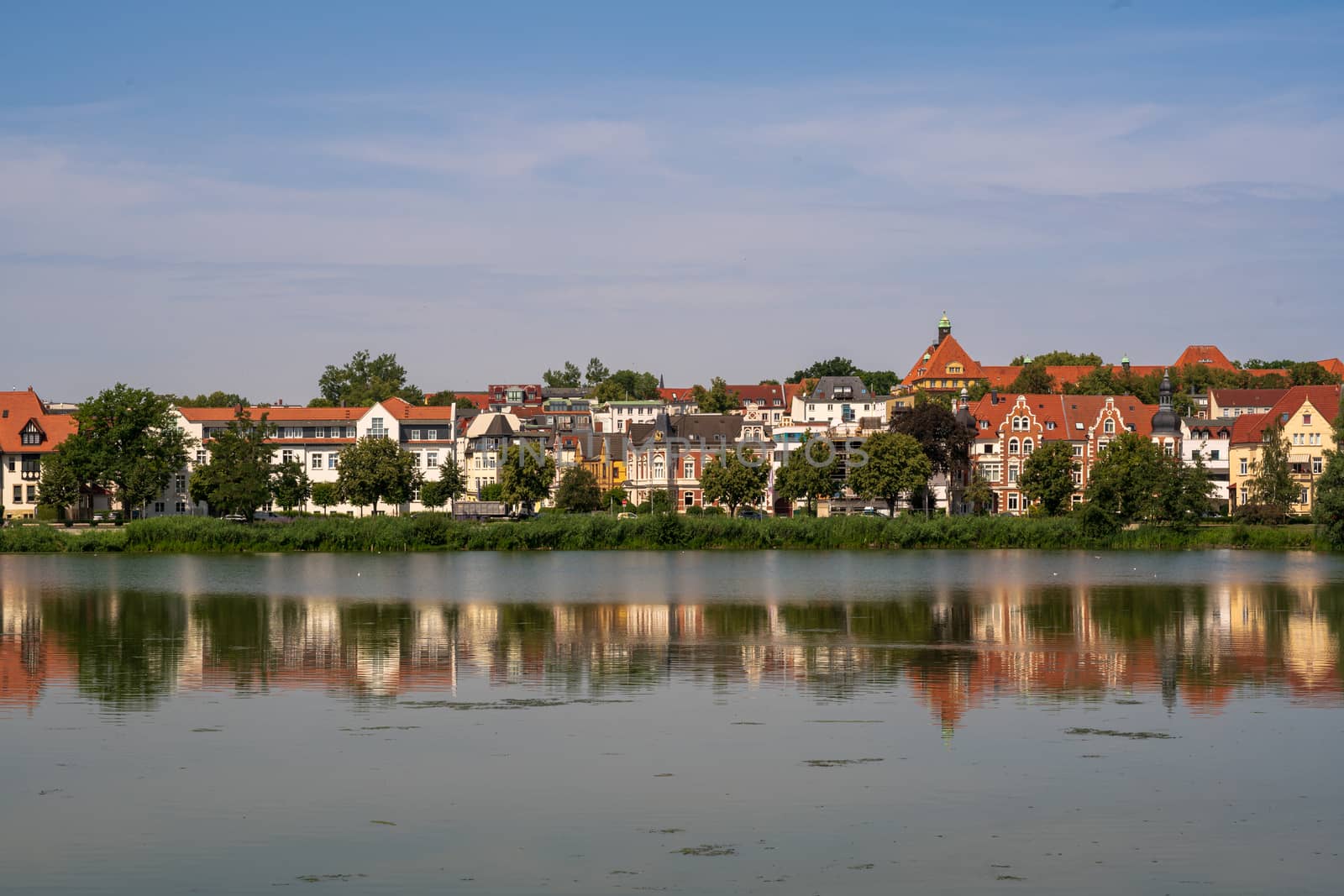 Lakefront houses in Schwerin Germany are reflected in the waters of the lake on a summer morning.