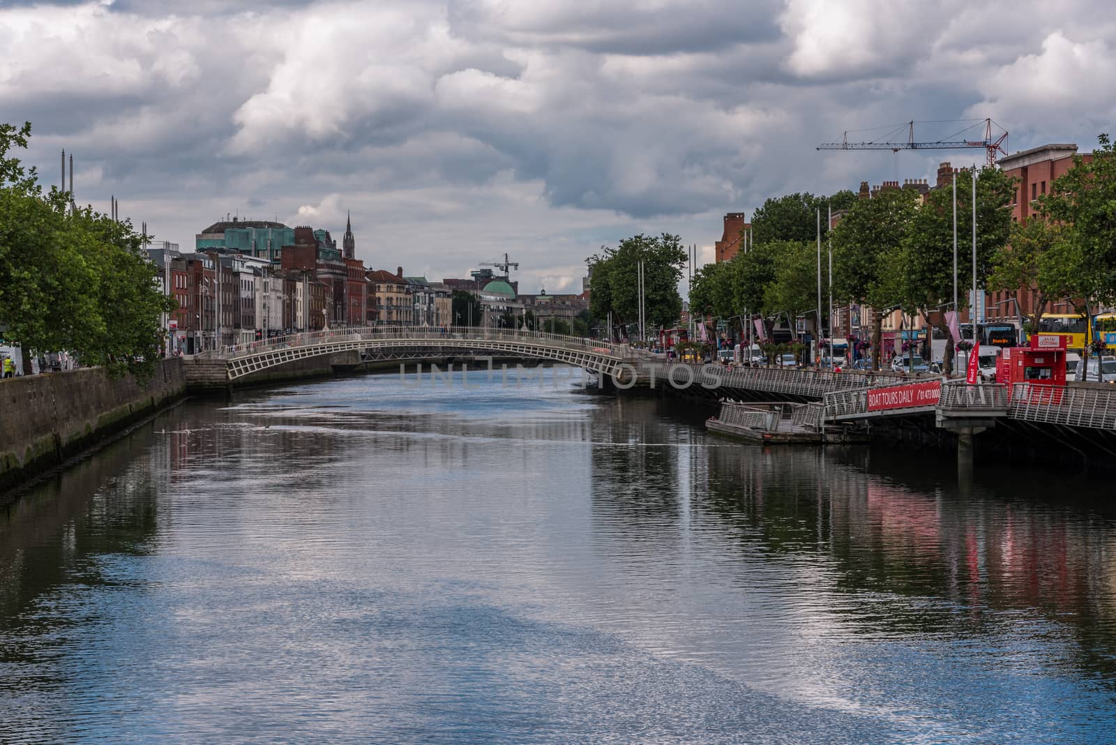 The River Liffey goes around a bend.  The river banks and bridges are busy with traffic, tourists and visitors.