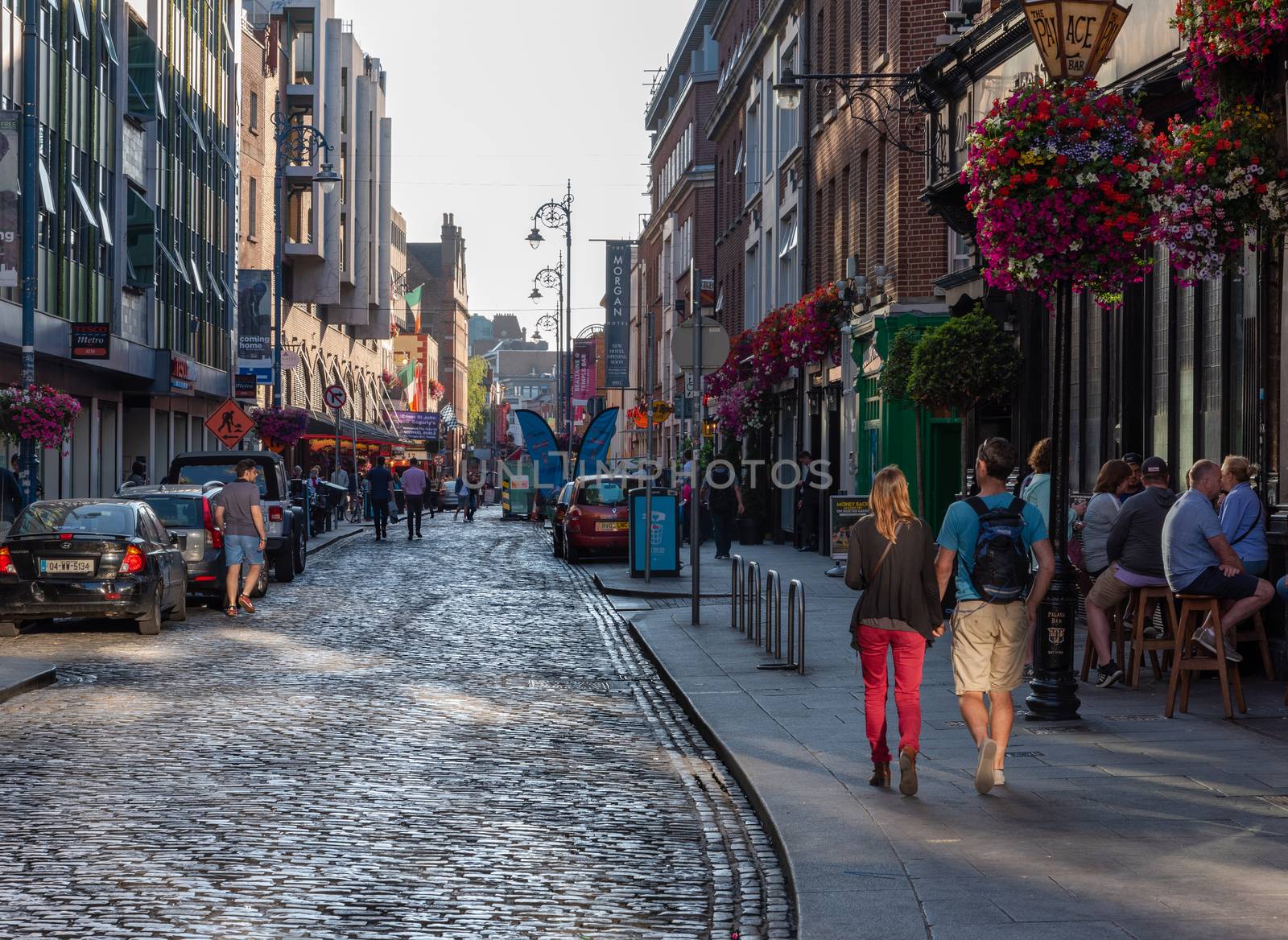 Dublin, Ireland -- JUly 9, 2018. A couple holding hands walks down a street in Dublin as the nightlife is about to get started.
