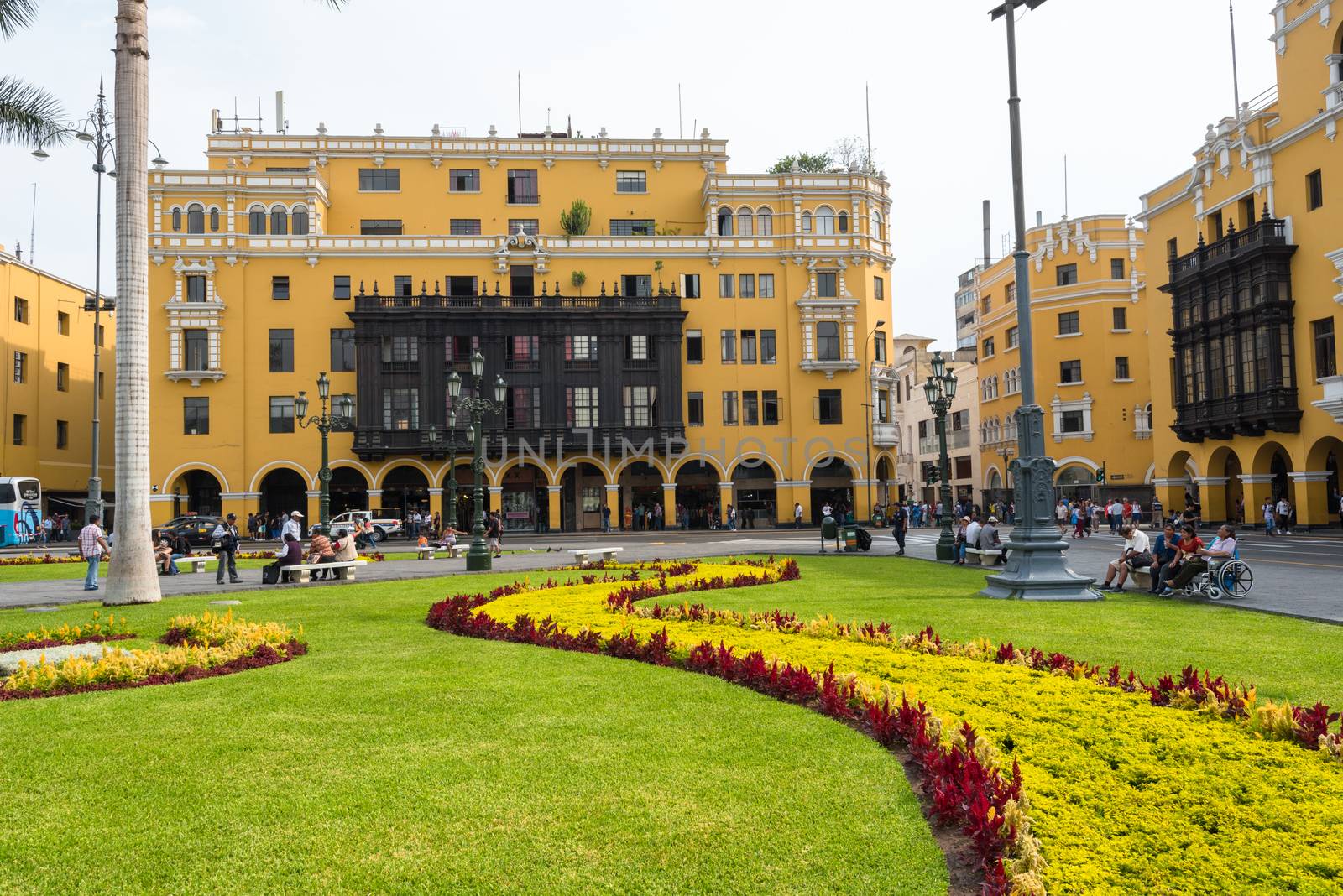 Tourists, residents and shoppers in the center of Lima Peru, the Plaza Mayor, with its flowers and yellow buildings.