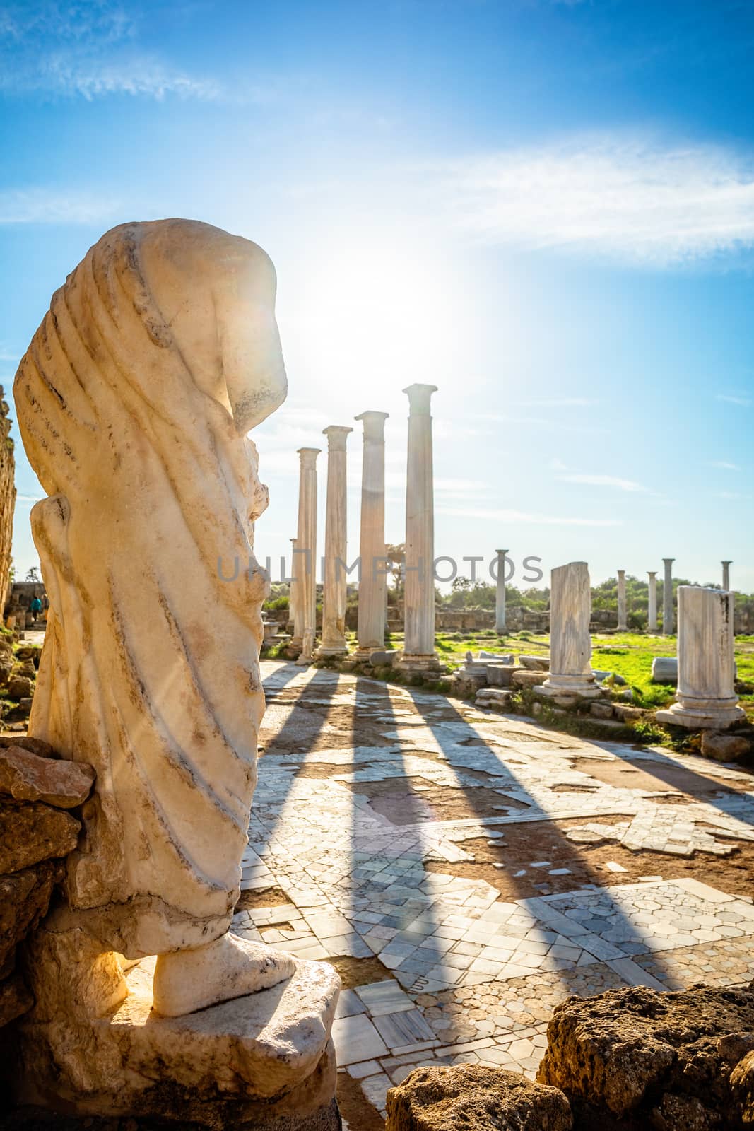 Marble statue under the sun rays and ancient columns at Salamis, by ambeon