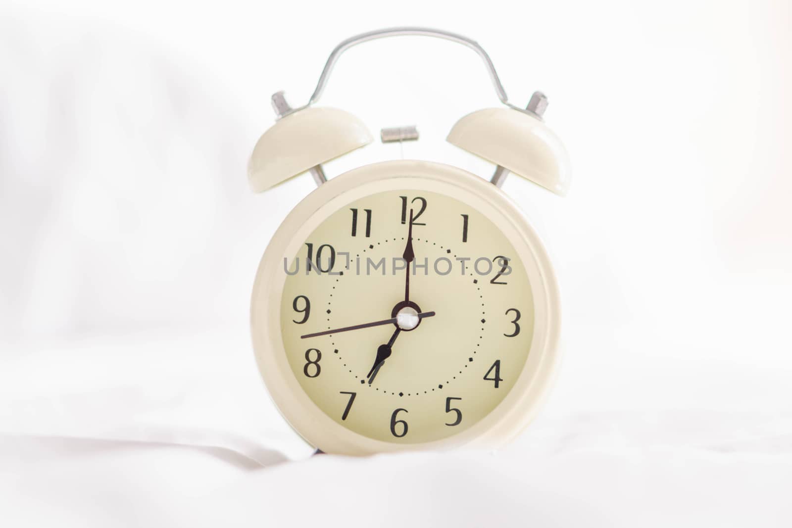 Alarm clock on wooden table for wake up time with light from window, selective focus