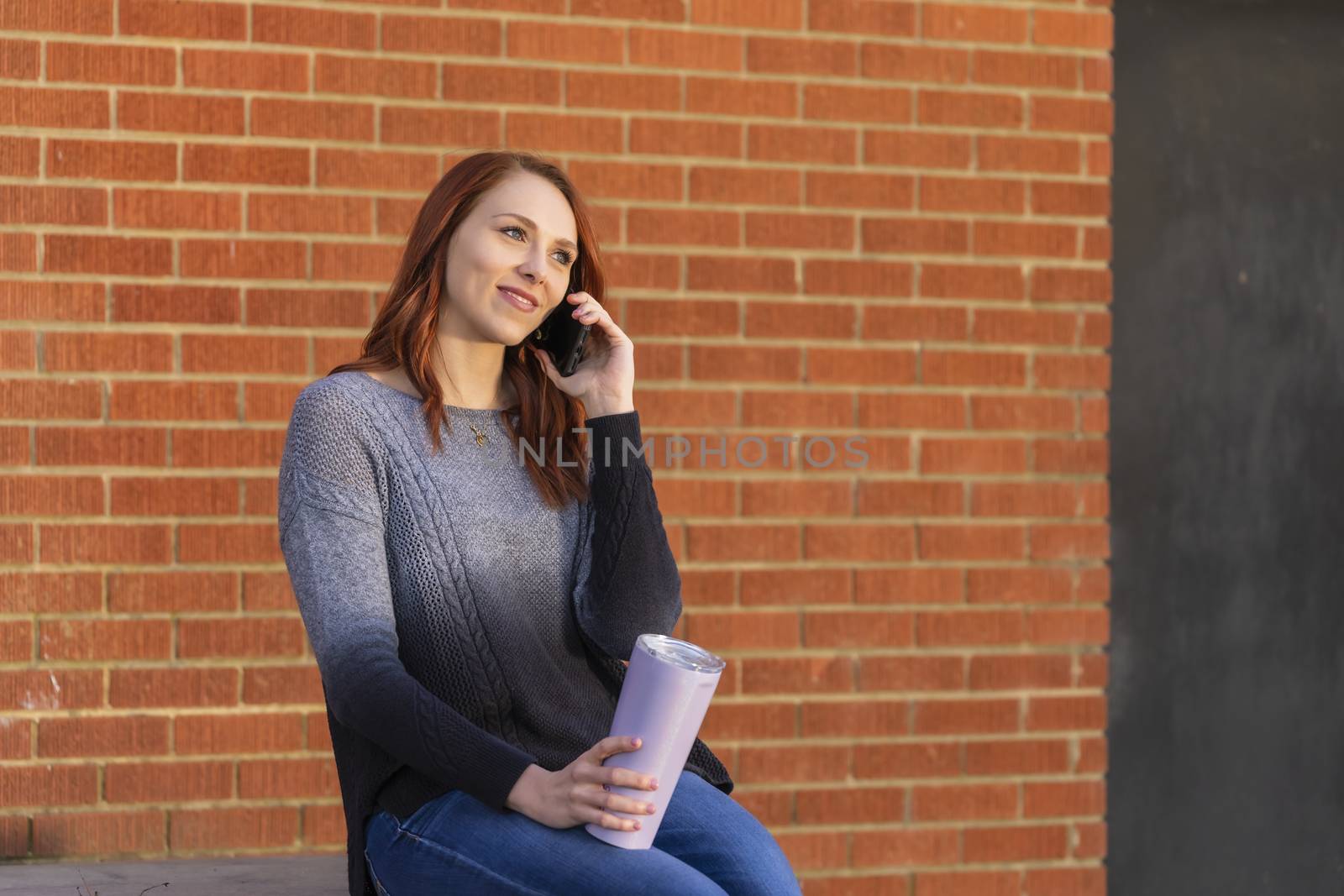 A Lovely Blonde Model Enjoys An Winters Day Outdoors While Drinking Her Favorite Drink And Talking On Her Cellphone by actionsports