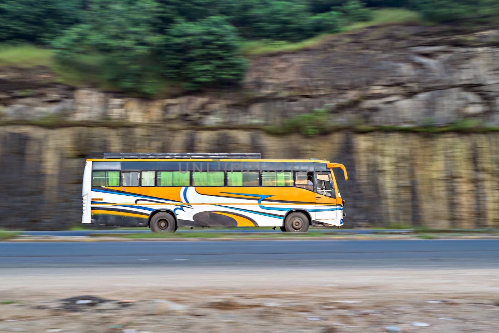 Panning photo of an yellow striped non-AC private travels bus , speeding towards Mumbai.