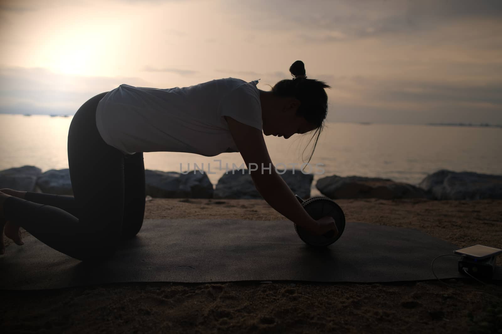 The silhouette of a beautiful woman practicing yoga on the beach by noppha80