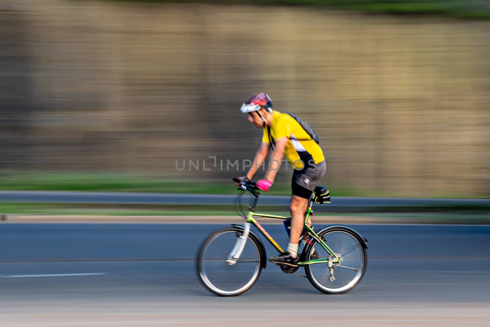 Pune, Maharashtra, India - October 4th, 2017 : Motion blur, panning image of a bicycle rider wearing helmet for safety on a way . by lalam