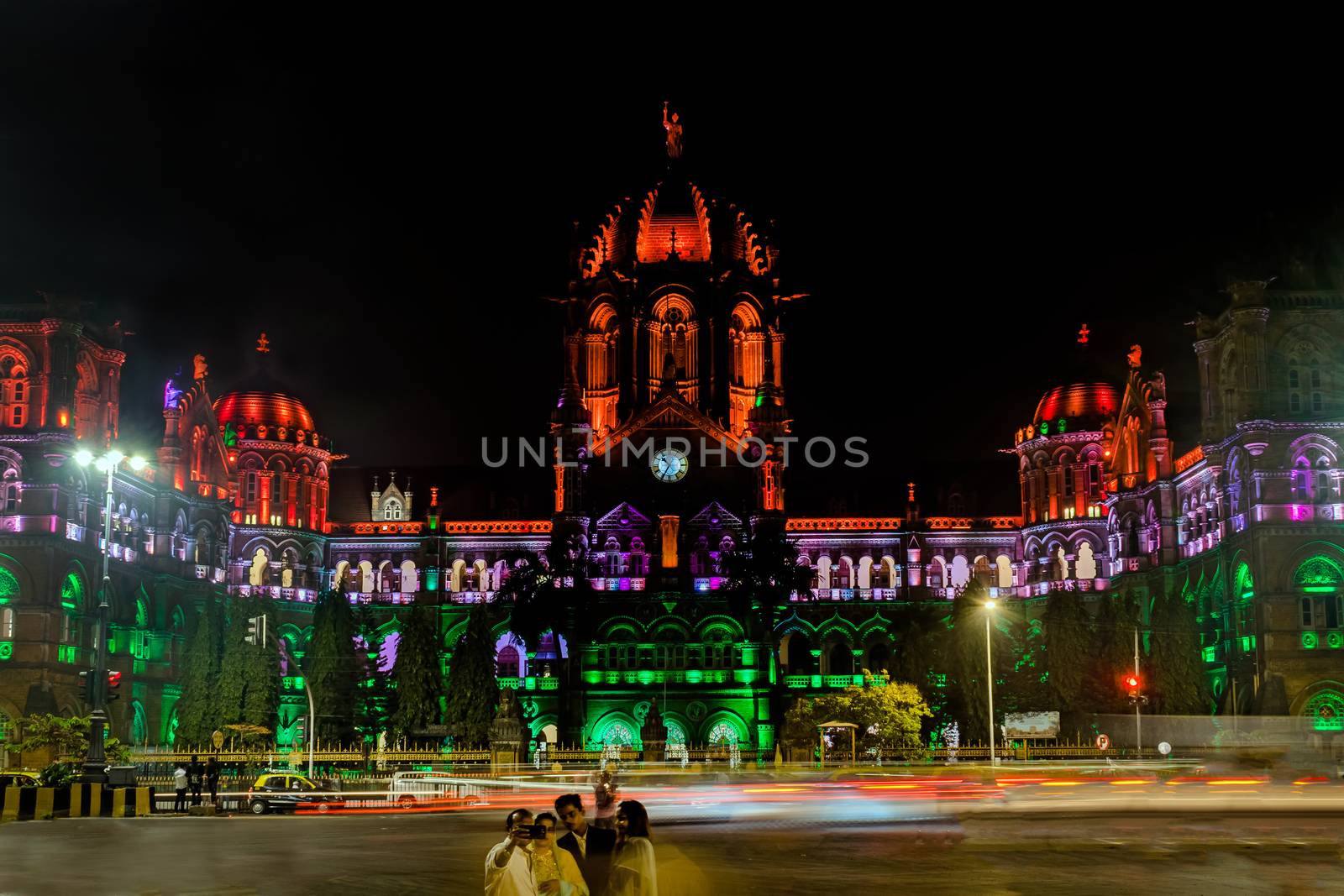 A family takes selfie against  UNESCO heritage building of `Chatrapati Shivaji Maharaj Terminus` railway station specially lighted like Indian flag . by lalam