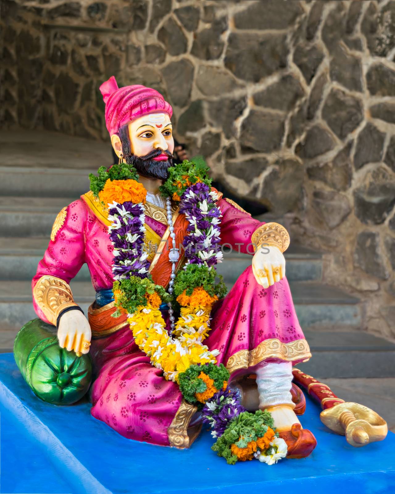 Pink colored Garlanded idol of Chatrapati Shivaji Maharaj placed on a table.