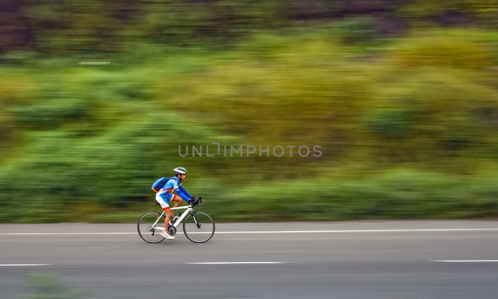 Pune, Maharashtra, India - October 1st, 2017 : Motion blur, panning image of a bicycle rider wearing helmet for safety on a way fo by lalam