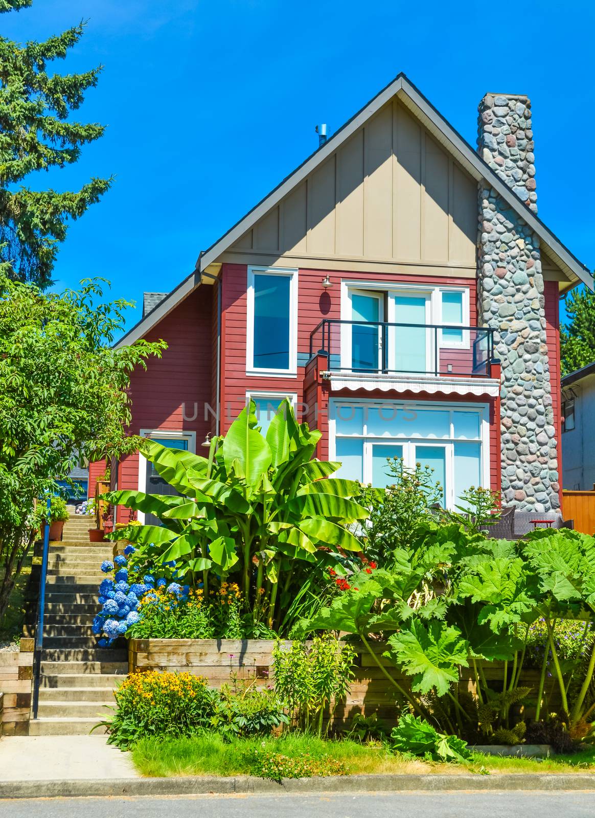 Beautiful suburban house with landscaped terrace and blue sky background. Residential house at sunny day in British Columbia