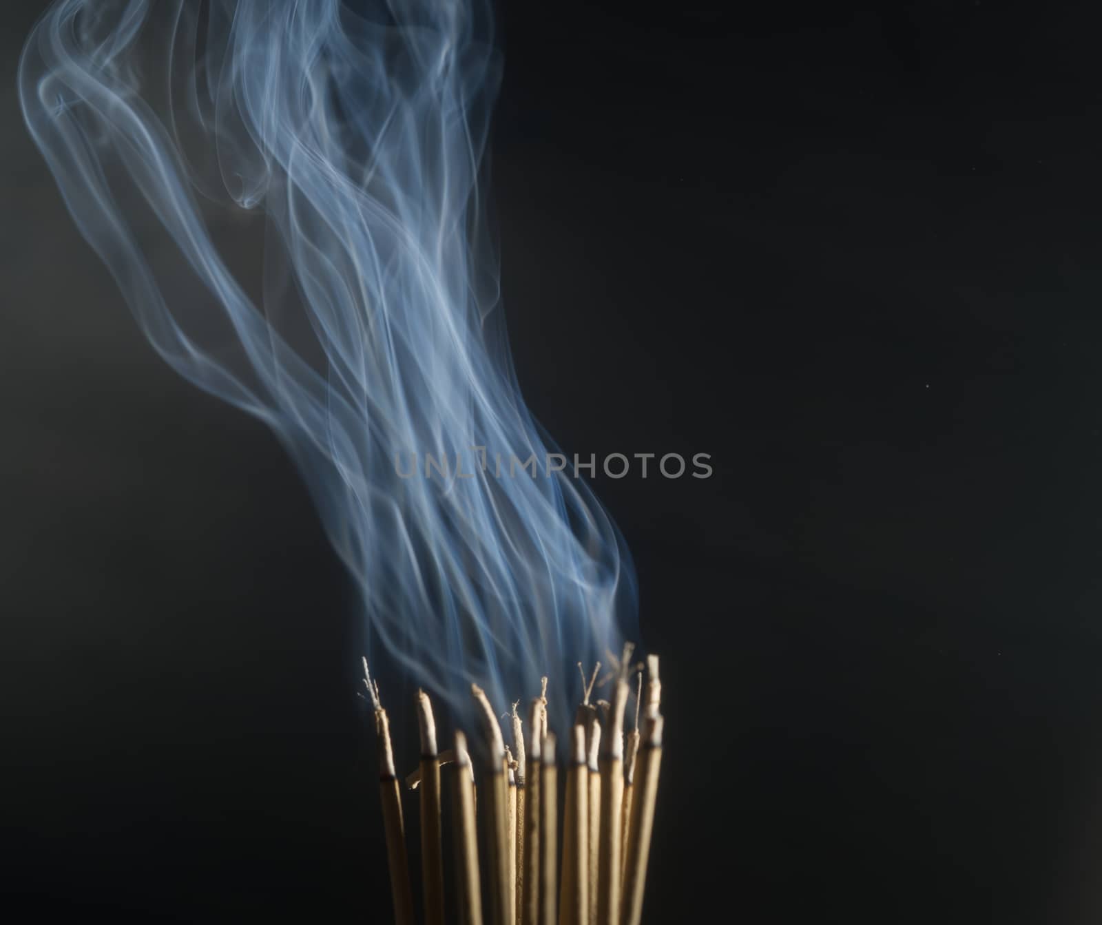 Incense burning incense, white smoke, black background, used as background image Paying homage to the sacred objects of the people of Buddhism according to their beliefs and beliefs.