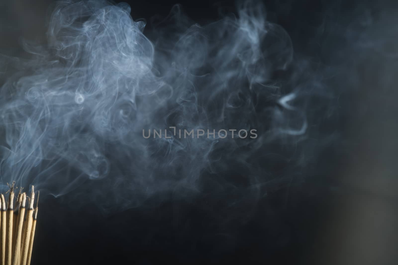 Incense burning incense, white smoke, black background, used as background image Paying homage to the sacred objects of the people of Buddhism according to their beliefs and beliefs.