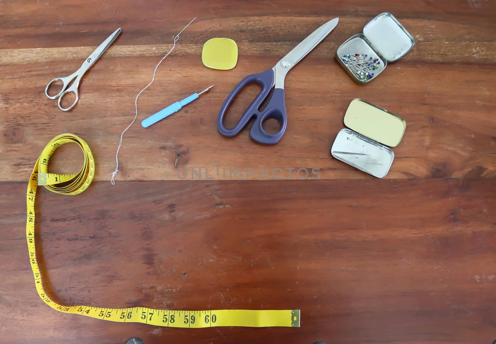 Different sewing accessoires on a brown wooden background. Sewing concept.