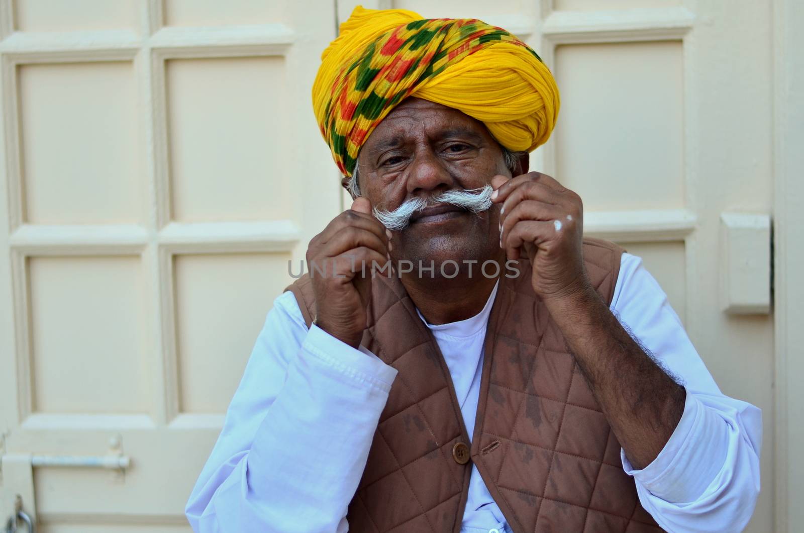 Jodhpur, Rajasthan, India, circa 2020. An old man cum gatekeeper wearing a yellow colorful turban showing off his mustache at the Mehrangarh Fort.
