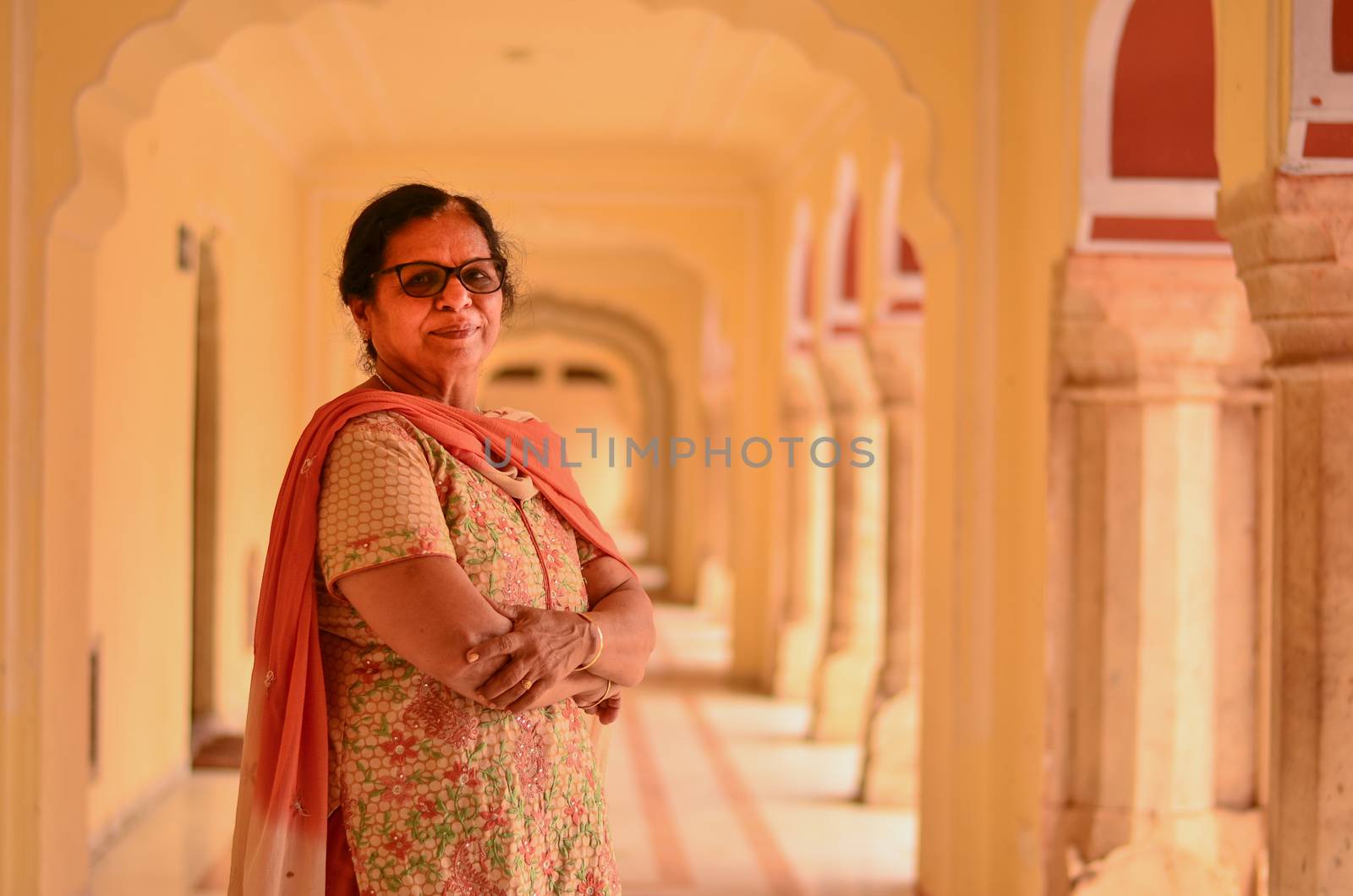 Happy looking senior Indian lady wearing traditional suit posing in the corridor of Jaipur's City Palace, Jaipur, Rajasthan, India by jayantbahel