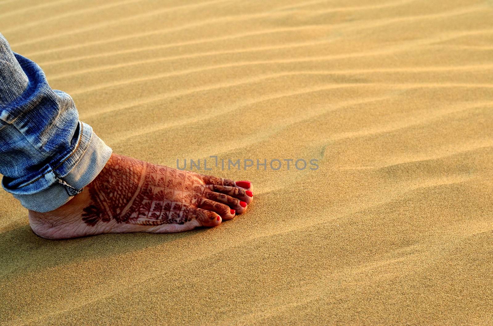 A newly married woman showing her foot with henna design in Sam Sand Dune, Thar desert, Jaisalmer, Rajasthan, India. Indian women apply henna on their feet and hands as a part of their wedding ritual