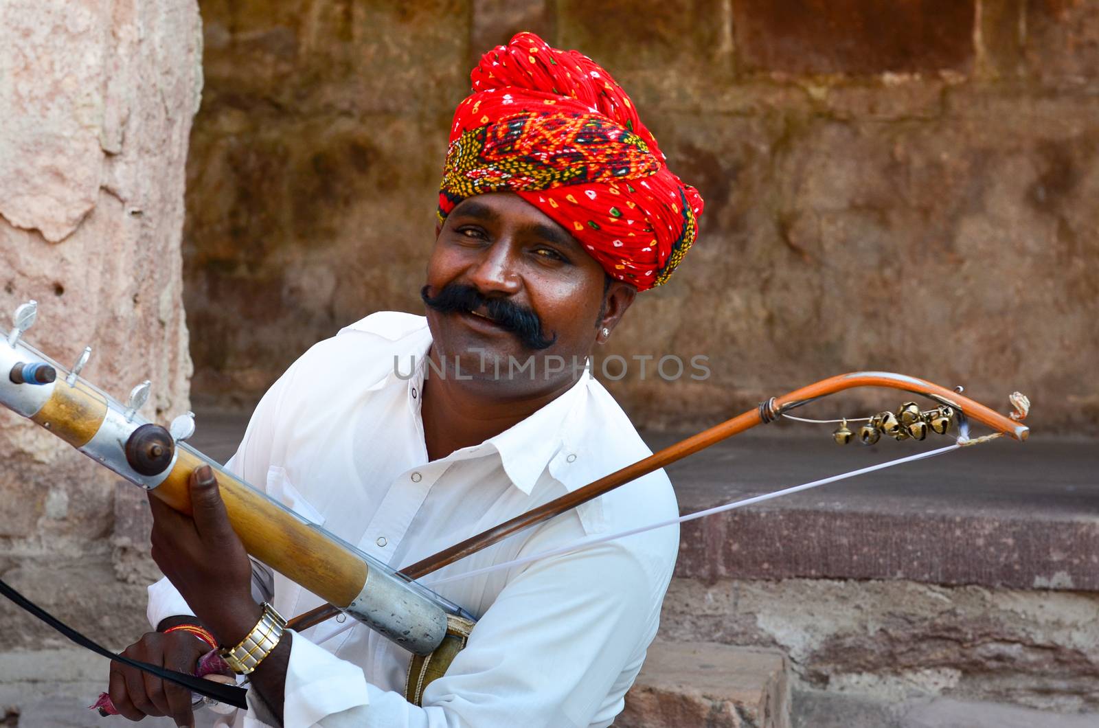 Jodhpur, Rajasthan, India, 2020. Closeup of Traditional Rajasthani sarangi player in his traditional dress and head gear turban red pagdi playing sarangi in Mehrangarh Fort.