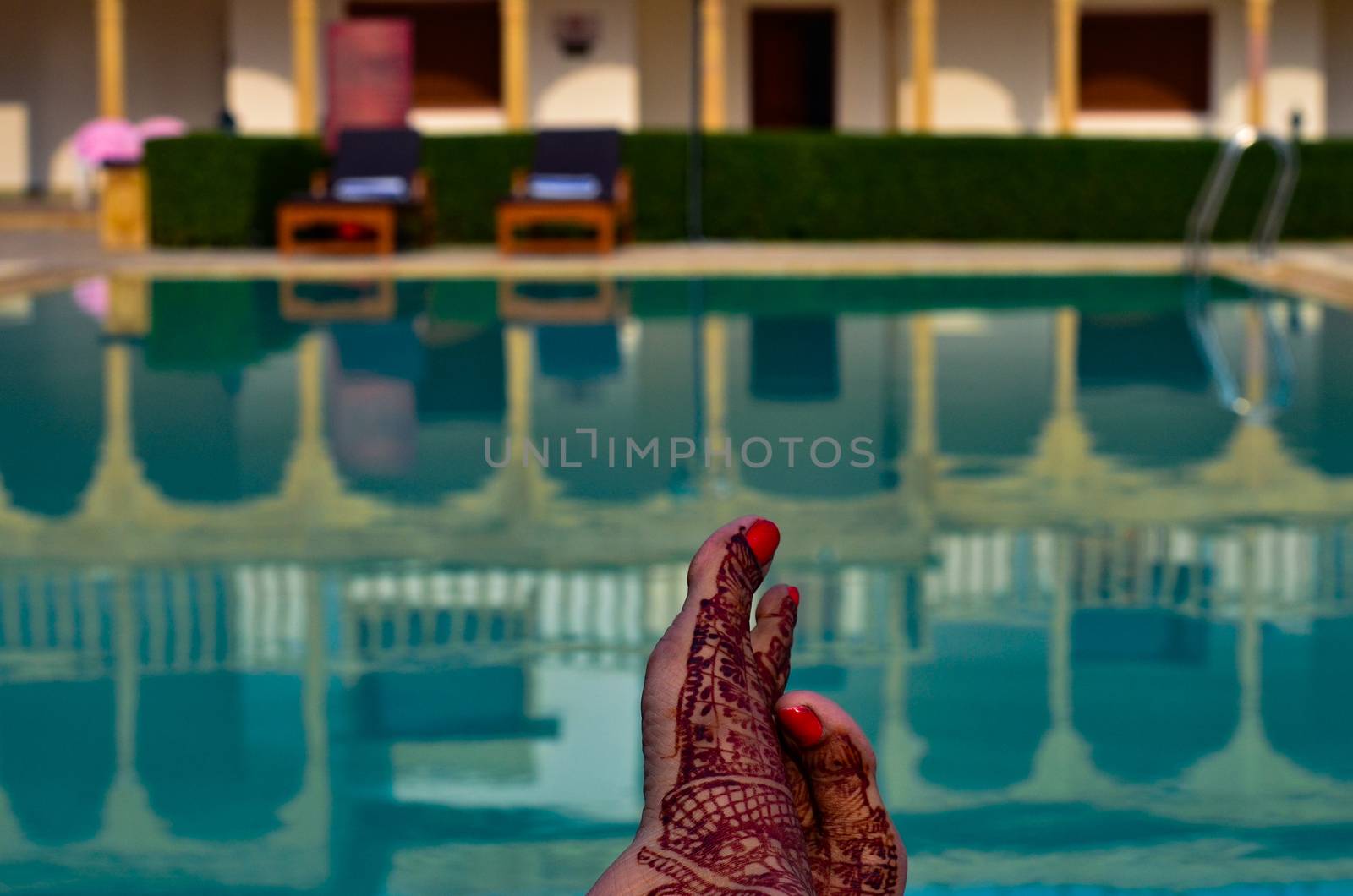 Newly married woman with henna feet in front of a swimming pool on her honeymoon in a resort in Jaisalmer, India