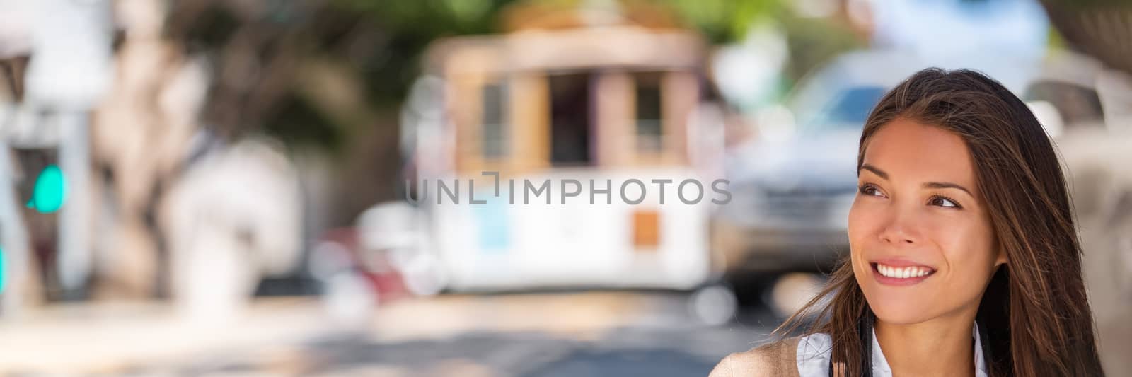 Asian woman portrait looking at panorama banner city background in San Francisco, California, USA. Young adult smiling at cable car tramways street lifestyle.