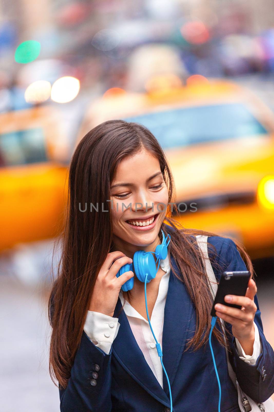 Headphones young woman walking in new york city using phone app listening to podcast or audiobook with earphones commuting from work. Asian girl businesswoman using cellphone.
