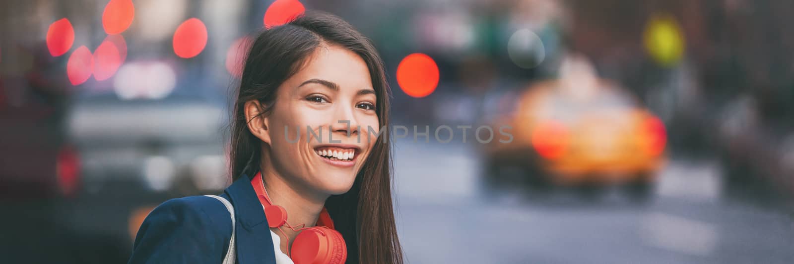 People city lifestyle young happy Asian woman walking in New York City street urban background with red headphones. Panoramic banner header.