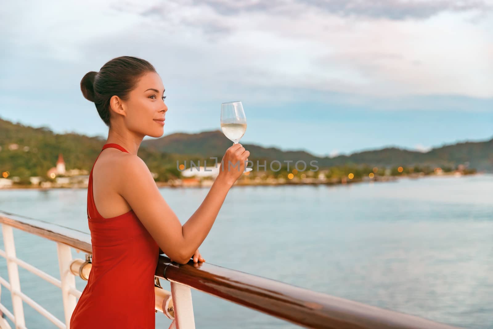 Luxury cruise ship travel elegant Asian woman drinking wine glass drink enjoying watching sunset from boat deck over ocean in summer vacation destination. Cruising sailing away on holiday by Maridav