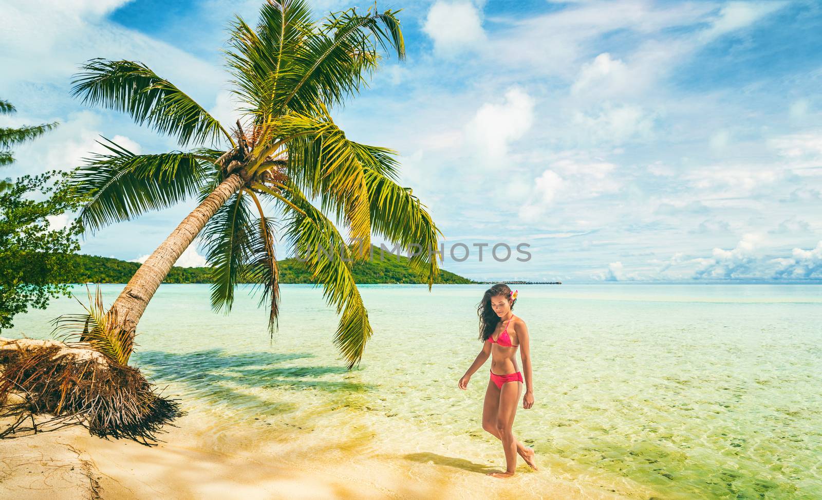 Luxury beach vacation Tahiti Bora Bora bikini woman swimming in paradise getaway destination. Beautiful Asian swimsuit model relaxing .