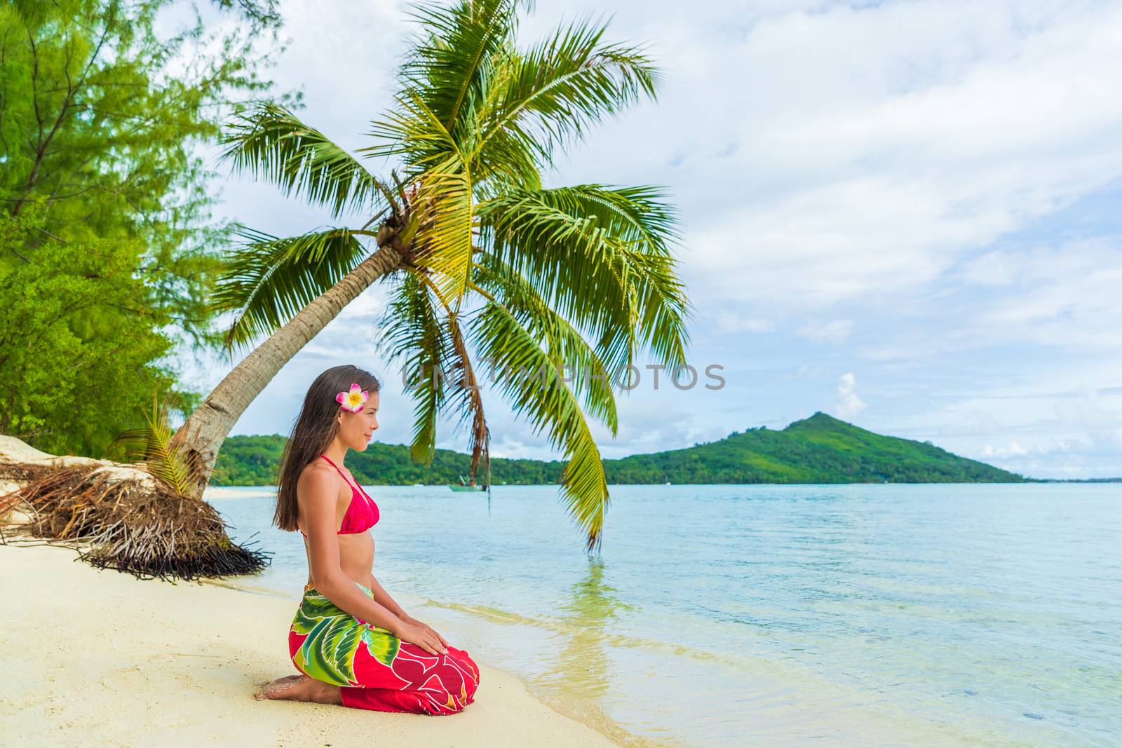 Tahiti Bora Bora French Polynesia Beach Vacation Travel Holidays. Woman relaxing sitting down on paradise beach on Matira Beach, Bora Bora. Happy girl wearing traditional pareo and Bikini in Tahiti