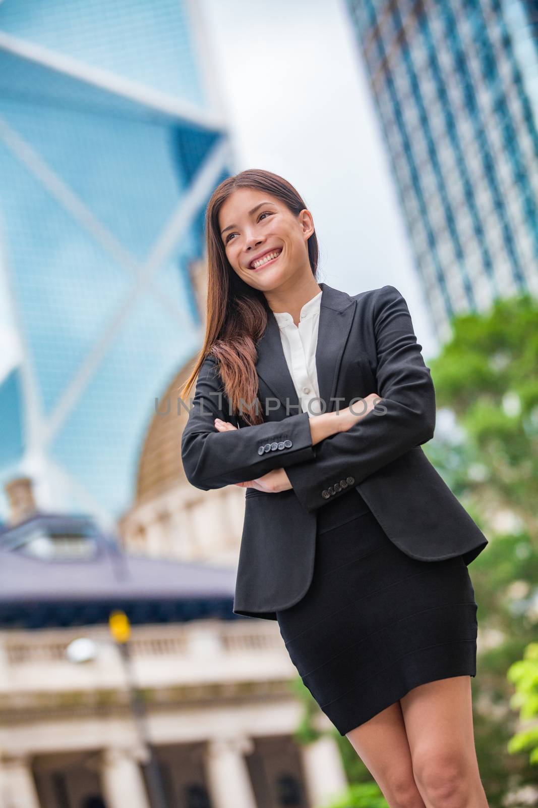 Business woman confident portrait in Hong Kong. Businesswoman standing proud and successful in suit cross-armed. Young multiracial Chinese Asian / Caucasian female professional in central Hong Kong by Maridav