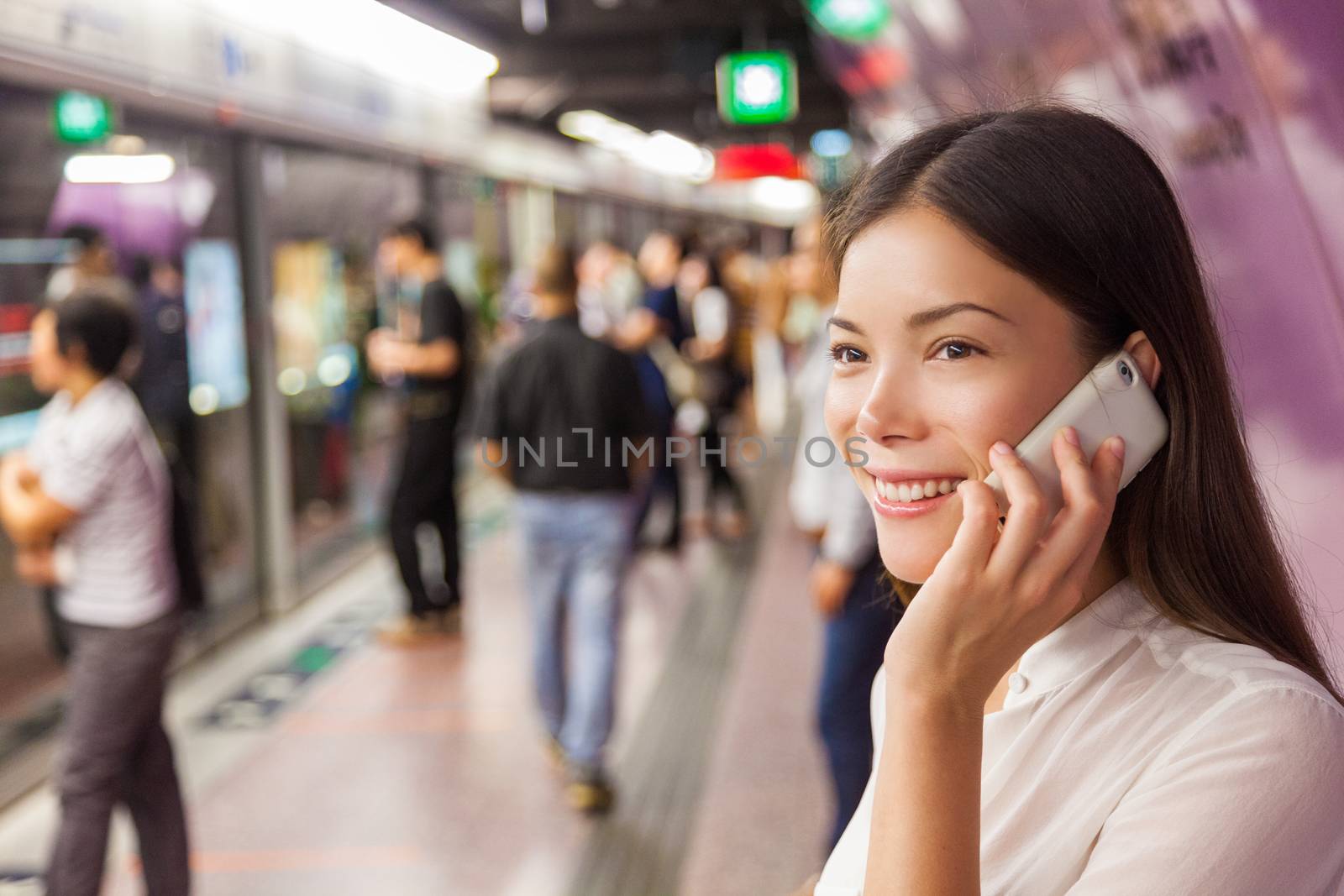 Businesswoman on subway metro commute public transport station talking on the phone while walking to arriving train. Asian woman happy using mobile cellphone app for conversation by Maridav