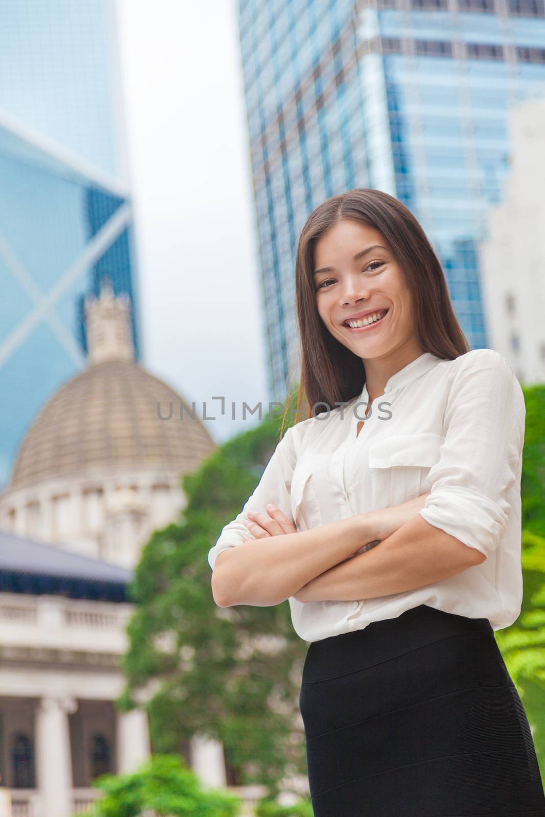 Happy confident young Asian business woman with arms crossed in urban city background, Hong Kong skyscrapers. Smiling businesswoman proud of working career, leader of success by Maridav