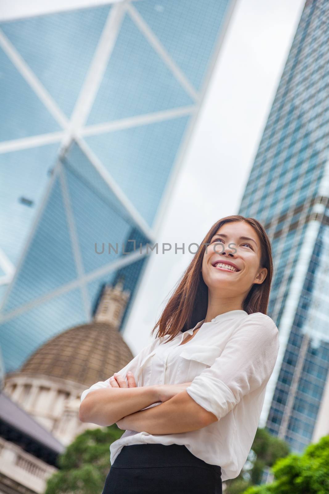 Asian business woman confident in Hong Kong. Businesswoman standing outdoor looking up in hope for future career with city background. Young multiracial Chinese Caucasian professional in Hong Kong.