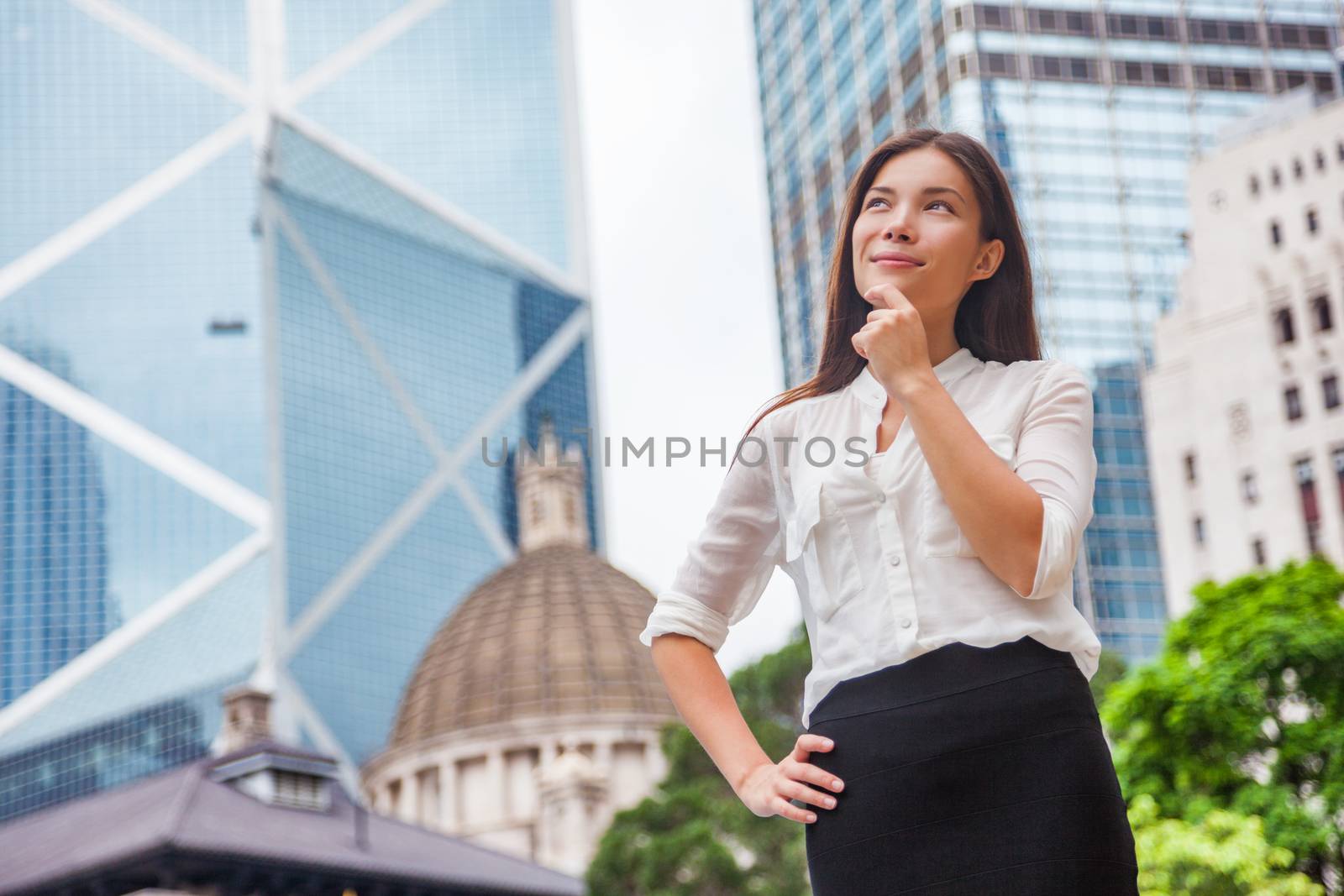 Asian business woman thinking pensive of career goal choice looking up at Hong Kong city, Asia urban lifestyle. Chinese girl holding finger on chin in formalwear office clothing choosing life path.