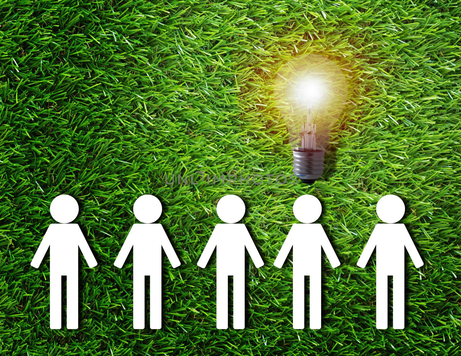 Think different concept, group of white paper people and light bulb on green grass background