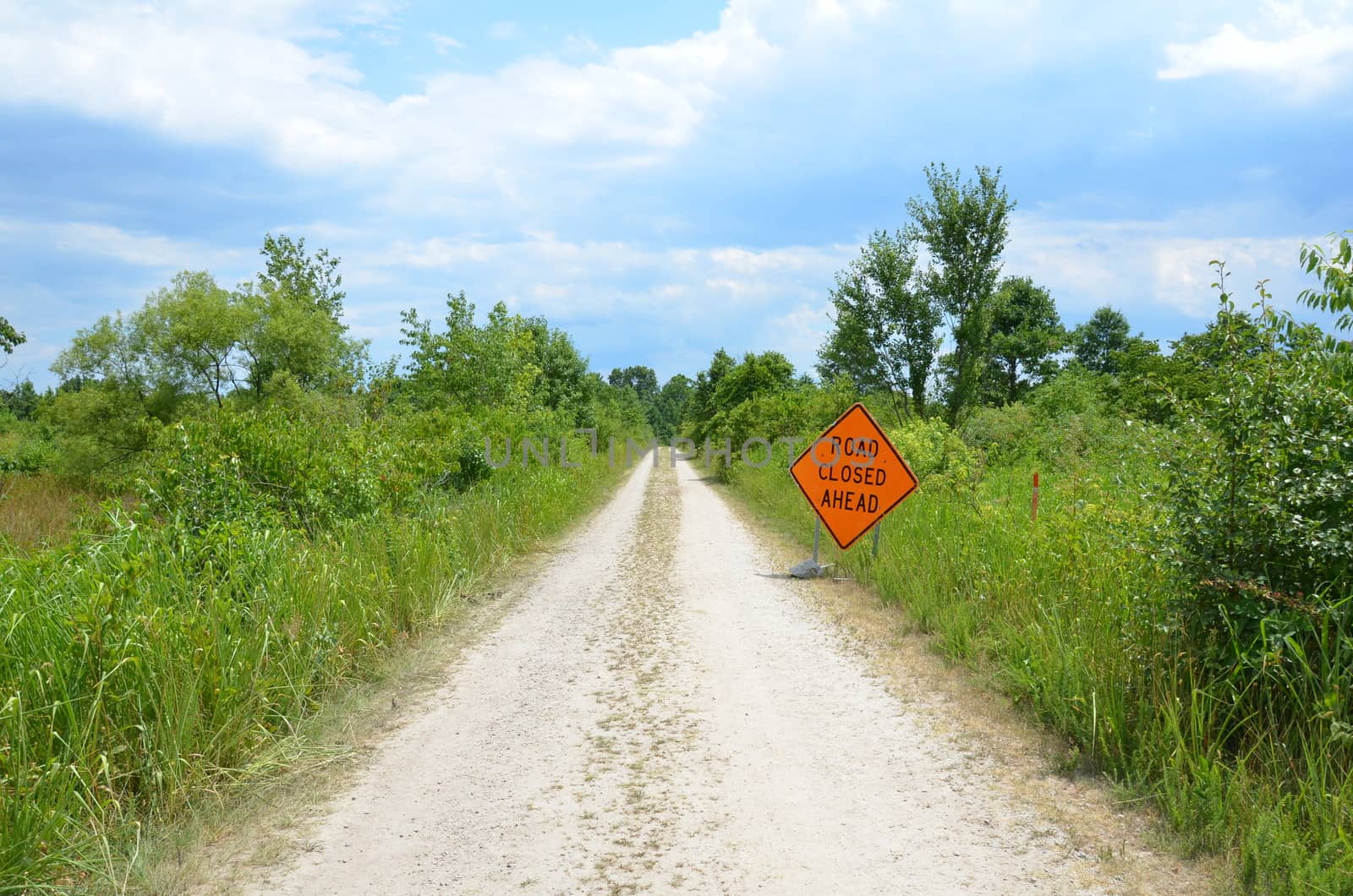 orange road closed ahead sign with path or trail