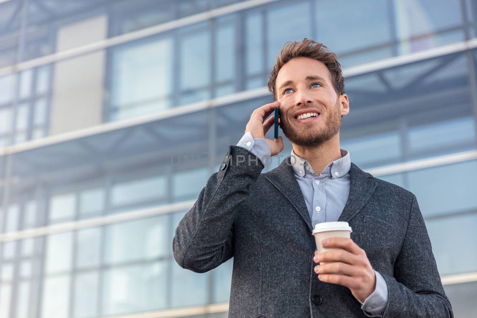 Man talking on smartphone. Businessman urban professional business man using mobile phone smiling drinking coffee at office building in city. Happy professional wearing suit jacket by Maridav