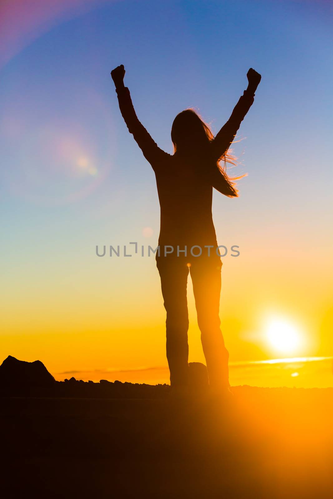 Winner woman winning with open arms in success of reaching mountain top in sunset flare, goal challenge achievement. Sport and active healthy living concept by Maridav