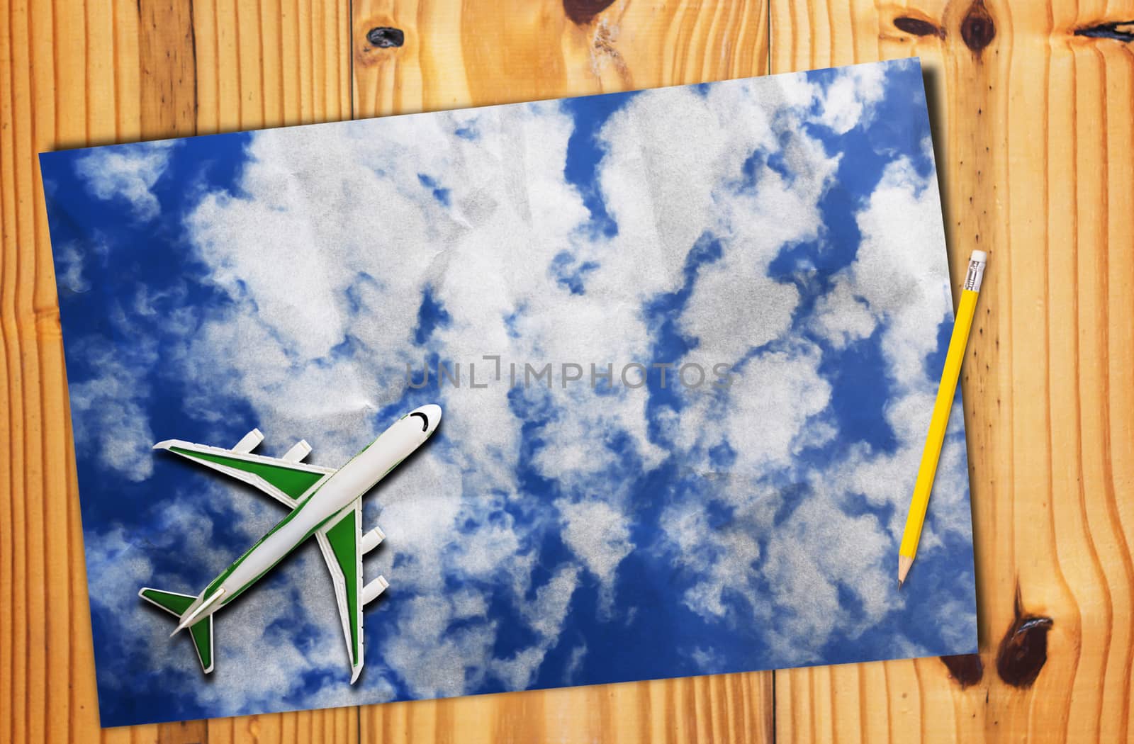 Travel concept, blue sky paper and yellow pencil on wooden table background