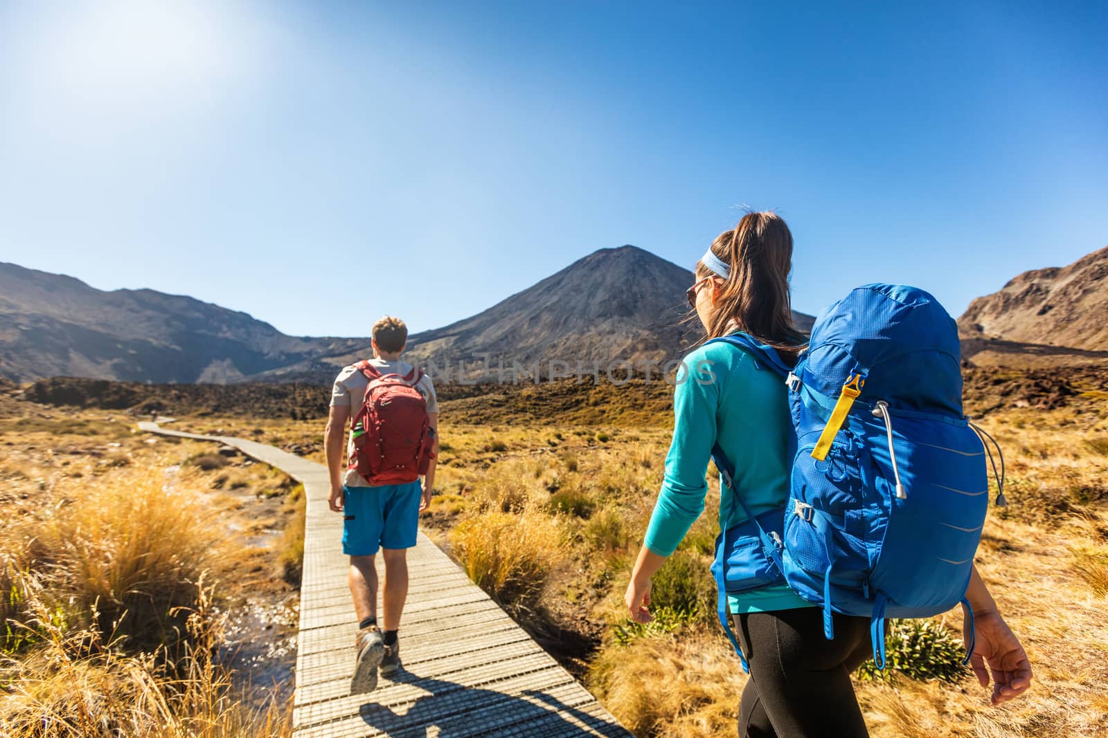 New Zealand Hiking Couple Backpackers Tramping At Tongariro National Park. Male and female hikers hiking by Mount Ngauruhoe. People living healthy active lifestyle outdoors by Maridav