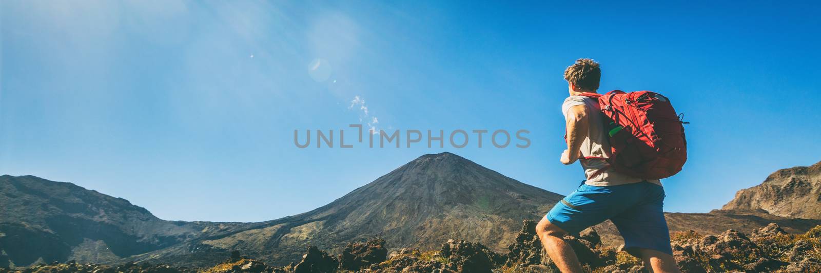 Hiker man hiking in banner landscape Tongariro National Park Alpine crossing hike trail man tramper tramping panoramic. North Island. Adventure travel traveler walking trek with bag backpacking.