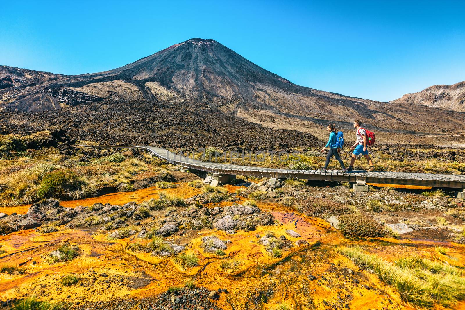 New Zealand Hiking Couple Backpackers Tramping At Tongariro National Park. Male and female hikers hiking by Mount Ngauruhoe. People living healthy active lifestyle outdoors by Maridav