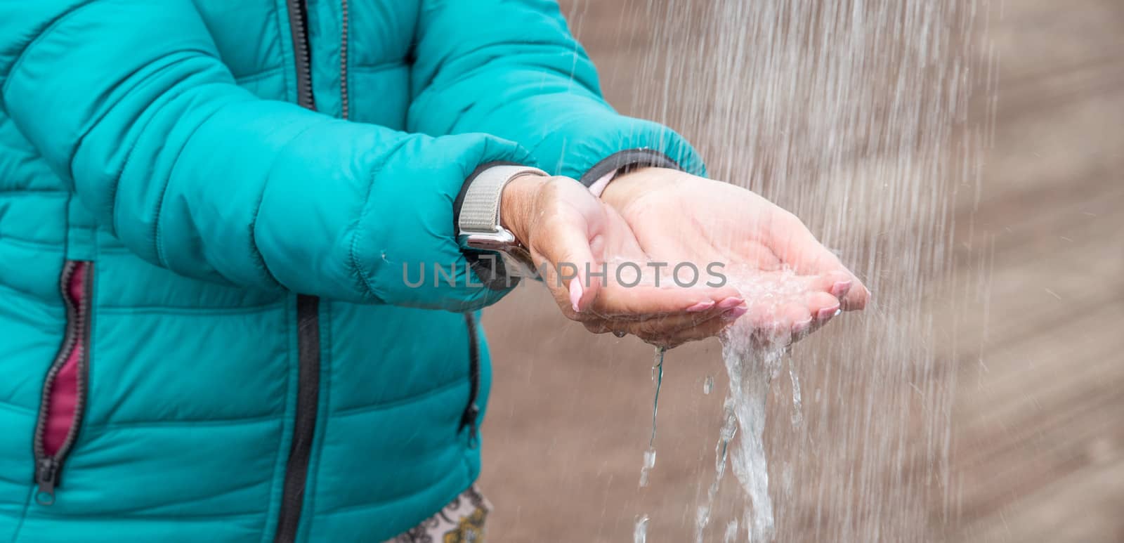 Thirsty woman capturing water from the shower with her hands outdoor in the countryside.